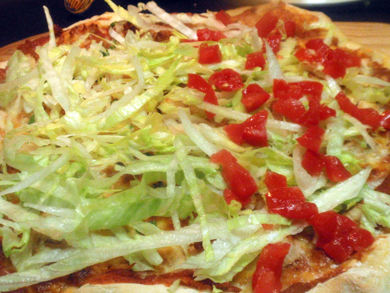 then fresh, cold shredded lettuce over top of the pizza, and fresh diced tomatoes on Tony's side